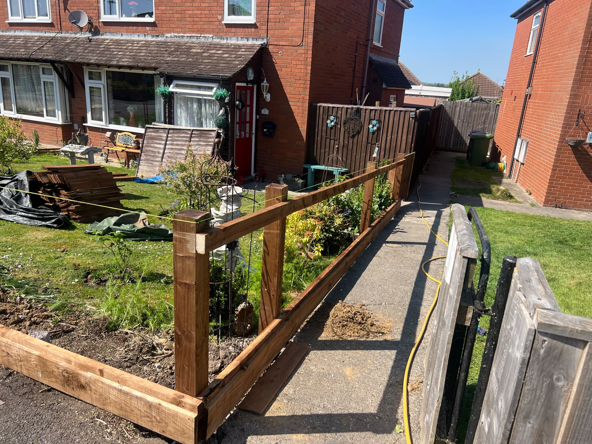 Fence posts and horizontal rails with a green string line and stacked slats on the lawn ready for boarding