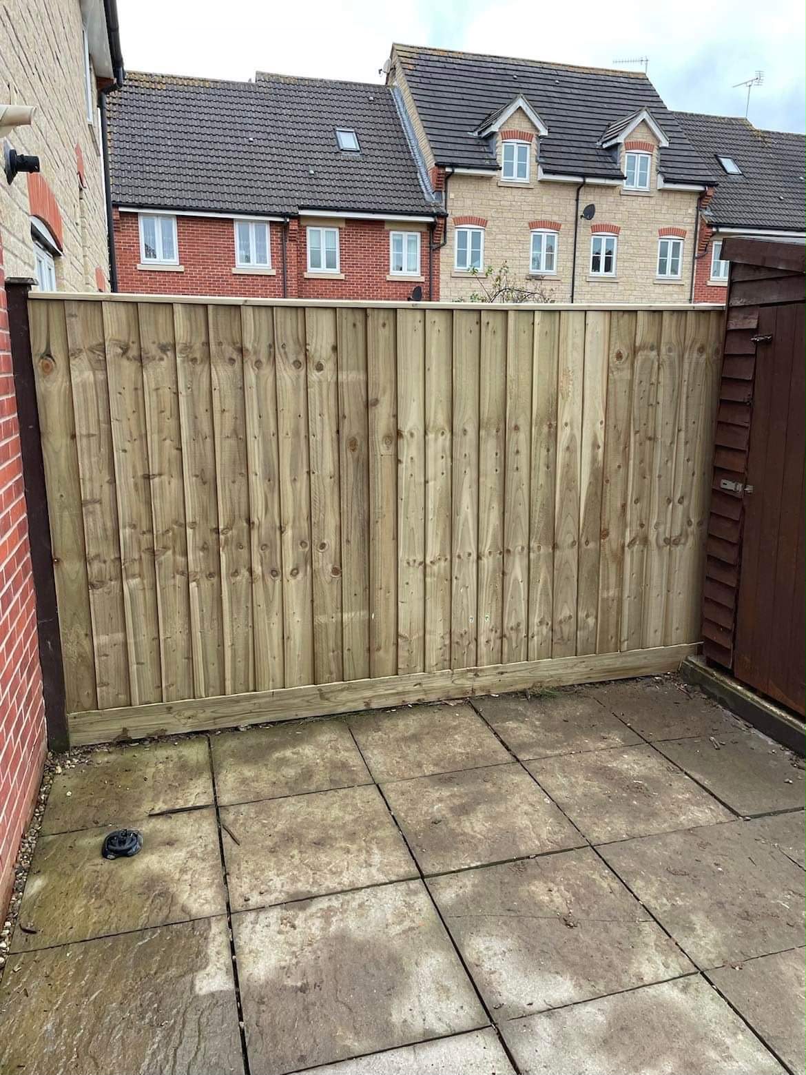New light timber featheredge fence with gravel board and capping rail between a brick wall and garden shed
